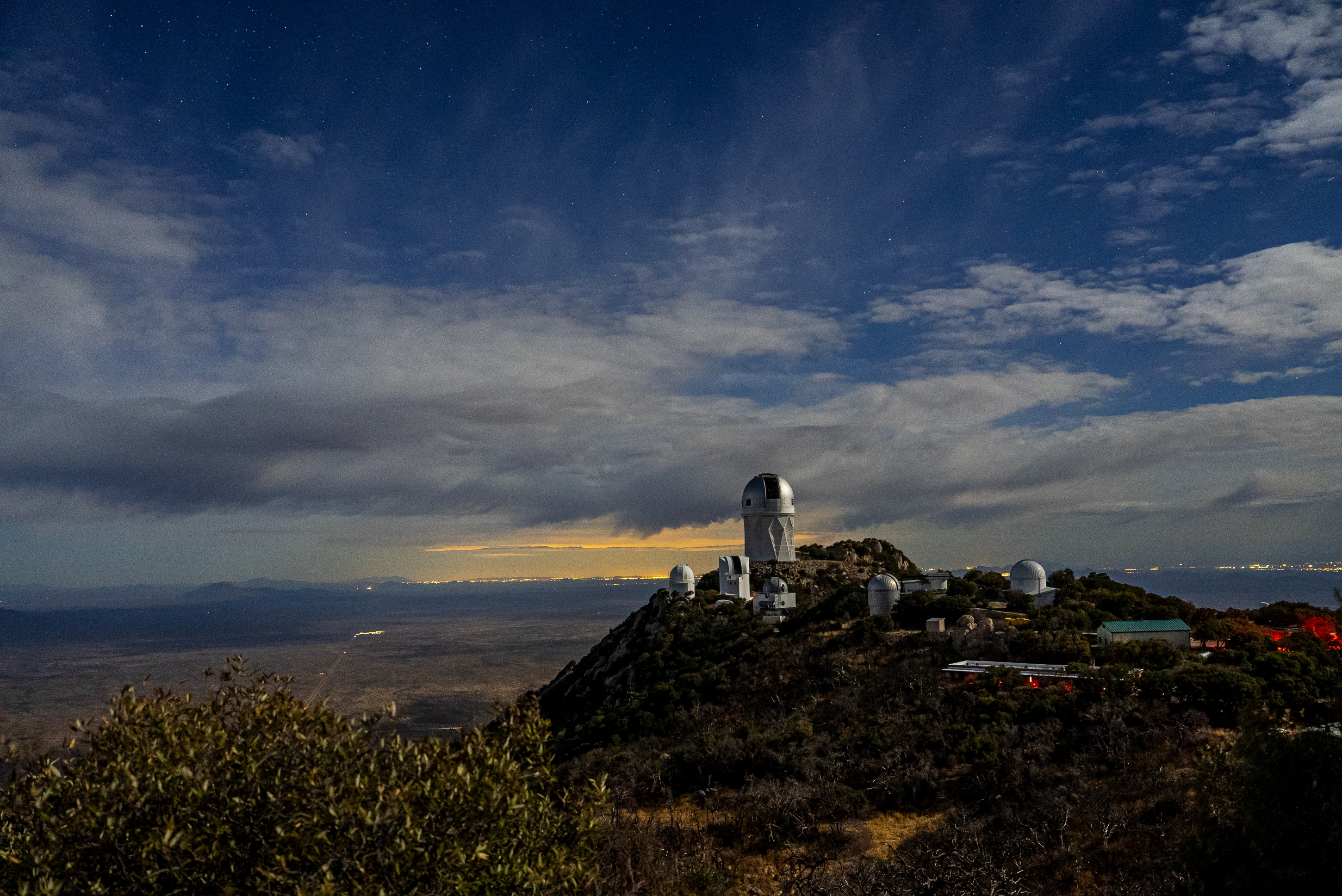 Multiple domed buildings on a mountainside. The sky is scattered with clouds.